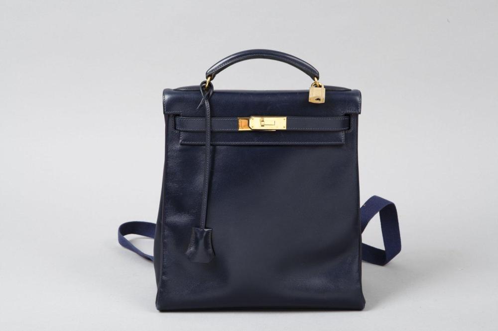 HERMES Paris made in FRANCE

Sac à dos «Kelly» 26 cm en cuir marine, fermoir, attaches plaqué or, cadenas, clefs dans sa clochette, sangle en tissus de même couleur au dos. Bon état