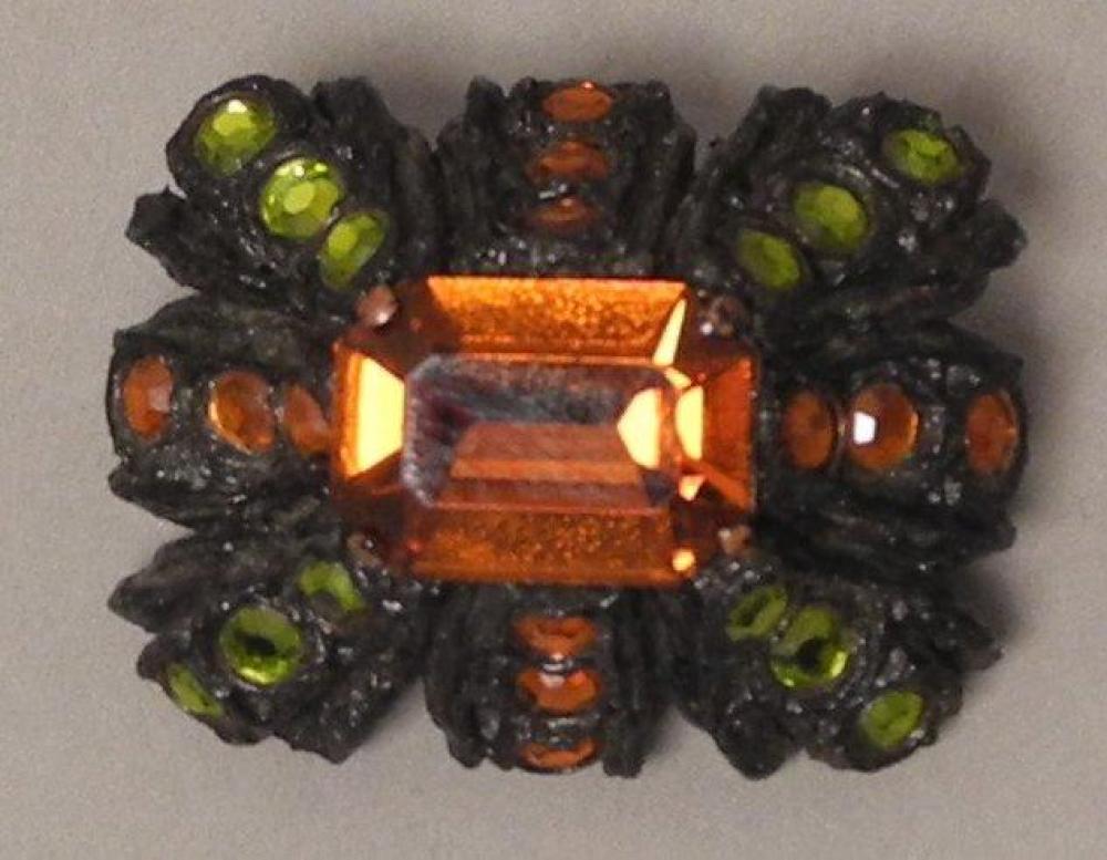 HENRY - circa 1960

Broche de forme rectangulaire en résine noire gravée et rehaussée de strass oranges et verts Signé