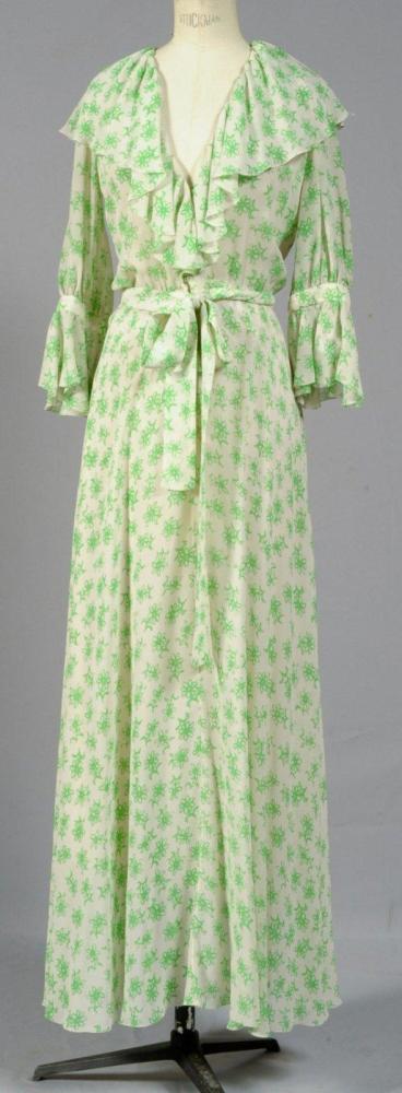 Christian DIOR

Haute couture 004022 Printemps-Eté 1974 Robe longue en mousseline imprimé de motifs floraux verts sur fond blanc, buste à col châle volanté sur décolleté en V, manches trois-quart avec rappel du volant, taille froncée ceinturée d’un ruban, jupe fluide. Griffe blanche graphisme noir