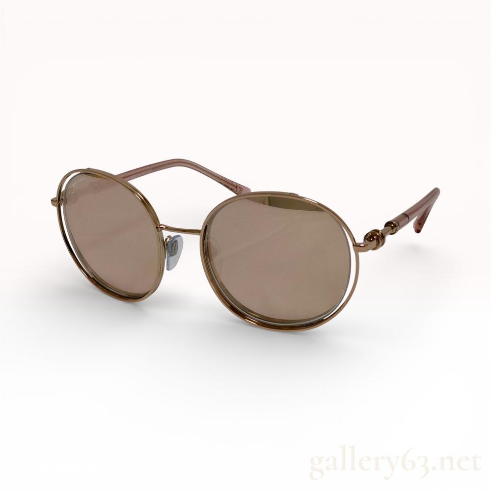Description
Bvlgari round sunglasses, model BV6169, featuring a floating lens design. Constructed with gold-tone metal frames, brown tinted lenses, and translucent pinkish-taupe acetate temple tips. The temples include architectural spacers inspired by the B.zero1 collection, with the brand name etched on the upper left lens and embossed on the earpieces. Includes original presentation box, hard-shell case, drawstring pouch, cleaning cloth, and Luxottica guarantee documentation.