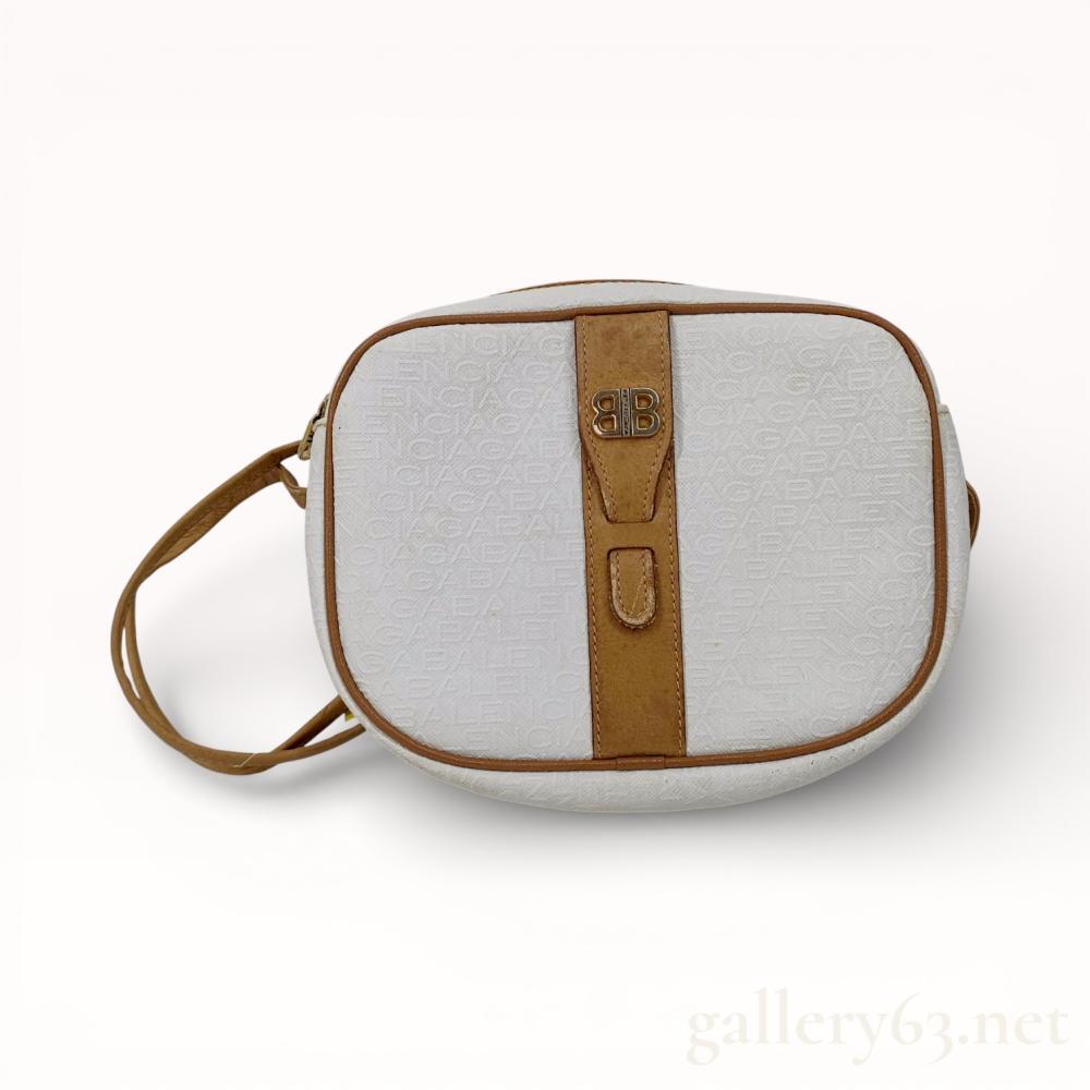 Description
Balenciaga vintage crossbody camera bag, late 20th century. The bag is constructed from white textured coated canvas with an embossed repeating brand name pattern and cognac-colored leather trim. It features a top zip closure with a gold-tone back-to-back B logo pull and an adjustable leather shoulder strap. An interior tan leather patch is stamped Balenciaga Paris Made in Italy.
7.5 inches x 6 inches.