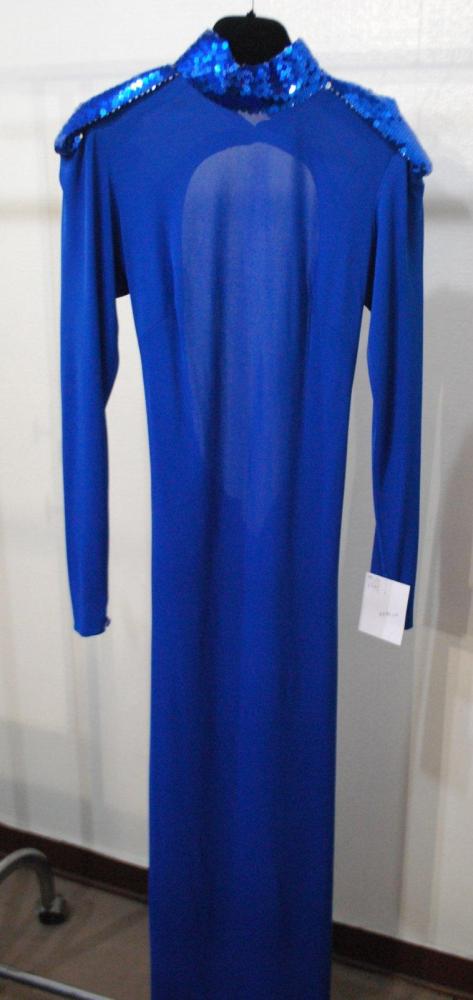 Loris AZZARO, circa 1975 / 1978

Robe longue en jersey polyester bleu "Klein", col droit recouvert de paillettes de même couleur, épaulettes à l’identique, dos nu jusqu’aux reins soulignant un boutonnage de la jupe droite. Griffe blanche, graphisme noir
