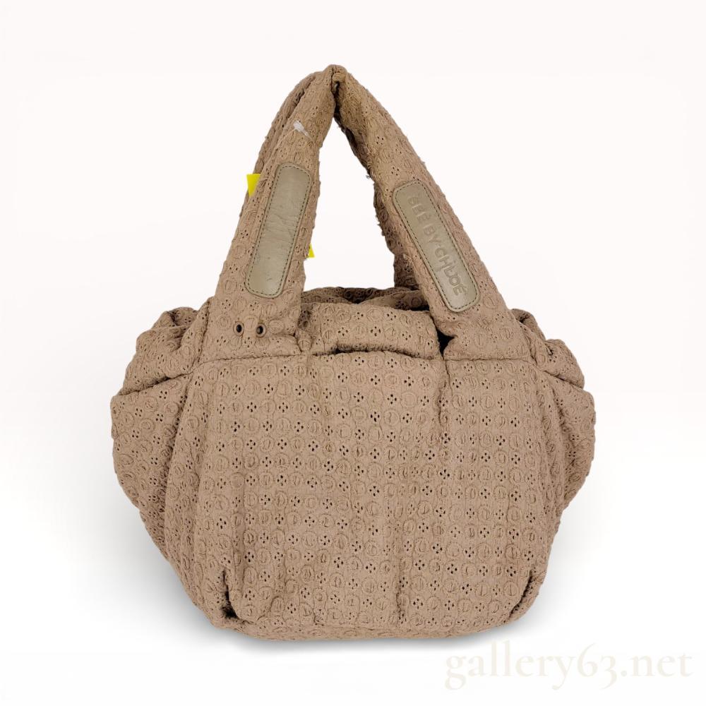 Description
See by Chloe puffed tote bag in a taupe textured fabric. The exterior features all-over tonal floral embroidery, eyelet detailing, and leather handle patches embossed with the brand name. The interior is lined in black textile with one zippered pocket and two slip pockets, secured by a tonal Vislon zipper with YKK hardware.
Approximately 15 inches wide at the base.