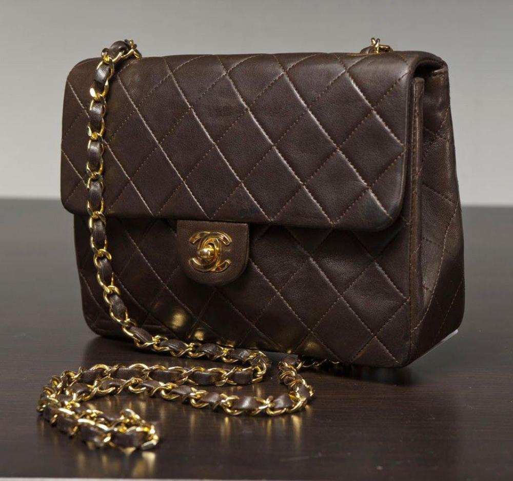 CHANEL

Sac en cuir agneau marron matelassé, fermoir siglé doré sur rabat, anse chaîne en métal doré entrelacé de cuir. Long: 20 cm