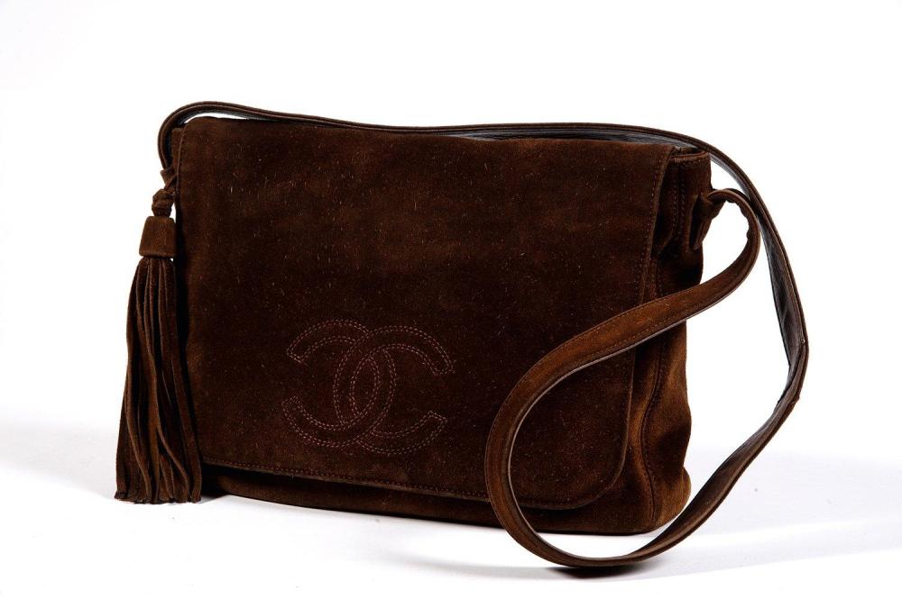 CHANEL

Sac besace 30cm en daim marron, rabat orné du sigle, anse bandoulière agrémentée d’un pompon, poche extérieure. (Salissures)
