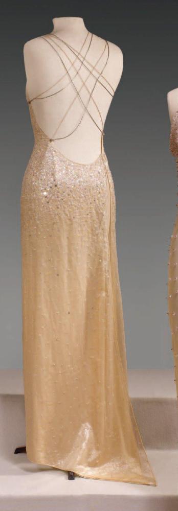 Gianni VERSACE

Robe du soir longue en organza chatoyant chair entièrement brodé de paillettes, d’étoiles, de perles translucides, encolure américaine sur un dos nu plongeant jusqu’aux reins, dos orné de filets de soie et métalliques s’entrelaçant, robe à très haute fente sur un côté. (petits manques) Griffe noire, graphisme blanc, or