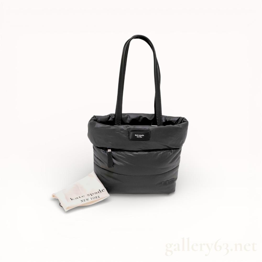 Description
Kate Spade New York Puffed Puffy small tote bag in black quilted nylon. The exterior features dual rounded leather shoulder straps, a horizontal zippered front pocket, and a rectangular logo plaque. The interior is lined with black fabric and contains a single zippered side pocket.
Approximately 12 inches width at base.