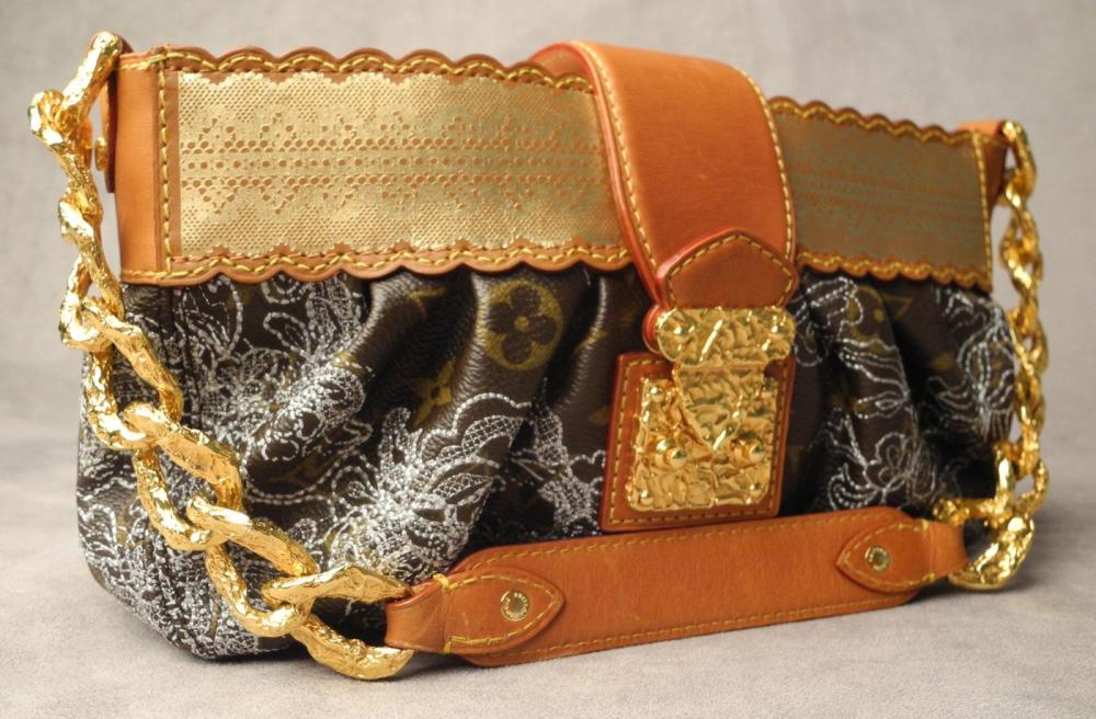 LOUIS VUITTON, par Marc JACOBS

Rarissime sac "DENTELLE KIRSTEN" Sac en toile monogram rebrodé de fleurs en fil argenté bordé de cuir naturel rehaussé d’une impression dorée à l’imitation d’un ruban de dentelle. Rabas en cuir naturel orné d’un fermoir en métal doré martelé Fermeture glissière en métal doré Intérieur en suédine grise avec une poche plaquée Anse chaîne en métal doré martelé rehaussé de cuir naturel L: 28 cm H: 18 cm EN TRES BON ETAT Avec son dustbag et sa boîte d’origine Edition limitée 2009 uniquement produite aux Etats-Unis Ce sac a été crée par Marc JACOBS en hommage au rôle de Kirsten Dunst dans le film "Marie-Antoinette"