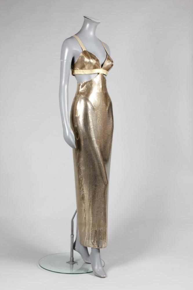 

A fine Gianni Versace golden-mesh ’Oscar’ dress, Autumn-Winter, 1994-95, with diamond Atelier label, the bra-bodice with top-stitched straps, the skirt attached in points to front and back, with kick-split to rear hem, integral gold lycra body, bust approx 92cm, 36in



Claudia Schiffer was photographed for US Vogue wearing an identical dress in a group photograph which included all the major super models of the period all dressed in opulent, draped golden mesh gowns of varying designs.
