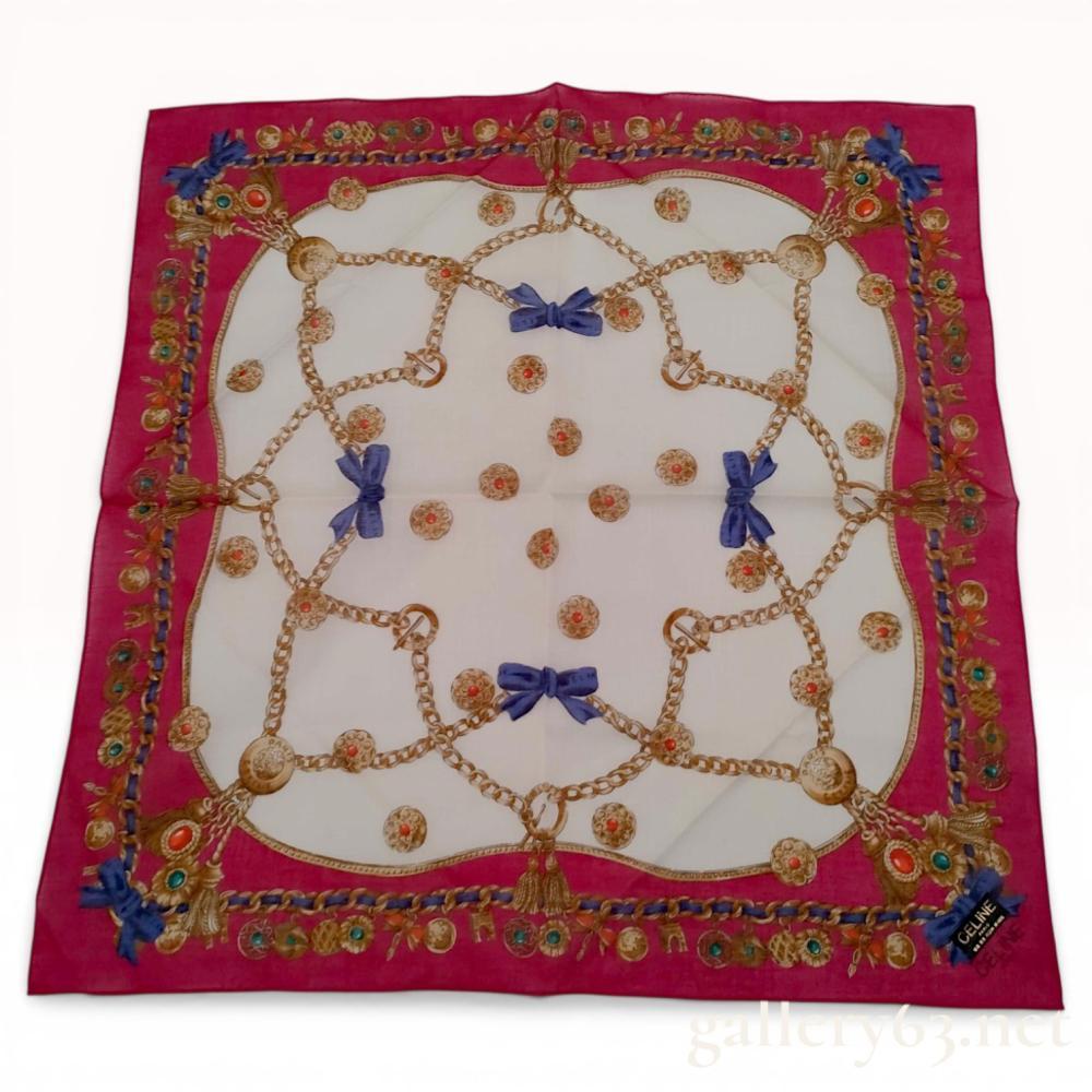 Description
Celine Paris square handkerchief featuring an ornate jewel and chain motif. The design incorporates gold chains, tassels, and cabochon charms in emerald green and coral red set against a white field and framed by a fuchsia pink border. The piece is finished with blue ribbons printed with the brand name and includes an original fabric tag.
Approximately 18 x 18 inches.