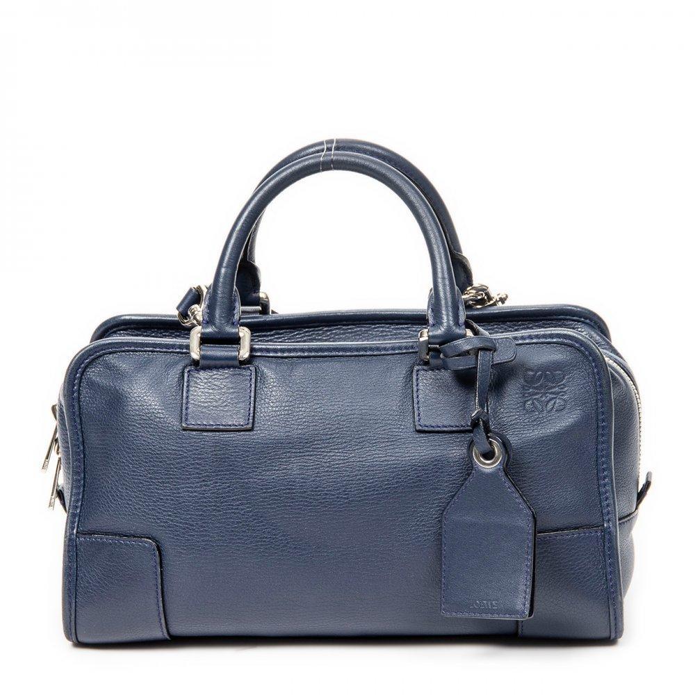 Description

LOEWE Amazona 28 bag.
Made of high quality leather in dark blue color, with soft finish and semi-rigid structure. Rectangular silhouette with leather reinforced corners, double top handle and double carriage metal zipper closure. Includes silver-tone hardware and charm pendant with padlock engraved with signature logo. Fabric lined interior with organizer pockets.
In excellent condition, light signs of use. Slight scuffs on the exterior and on the corners, small cracks on the handles and on the charm strap, as well as light scratches on the hardware.
Comes with strap, original pouch and luggage bag.
Measurements: 29 x 16 x 13 cm.

The Amazona model, launched by Loewe in 1975, is one of the most iconic bags of the Spanish firm. Its design, originally conceived as a work bag for the modern woman, is characterized by its balance between functionality and elegance. The size 28 is ideal for everyday use, while maintaining a compact and sophisticated aesthetic.

Founded in Madrid in 1846, Loewe is one of the oldest leather goods houses in Europe, renowned for its mastery of leather work and timeless style. The Amazona remains, to this day, a symbol of the firm’s discreet luxury and craftsmanship.