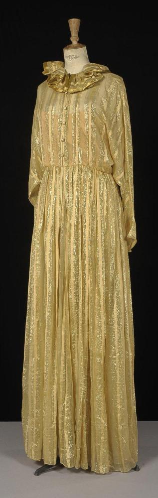 Bill BLASS, circa 1980

Robe longue du soir en mousseline et satin de soie beige rehaussé de fils lurex or, encolure ronde soulignée d’un double volant, buste à boutonnage brides, manches longues chauvesouris, jupe longue à deux épaisseurs. Griffe blanche, graphisme noir