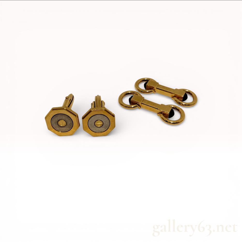 Description
Two pairs of men’s cufflinks, Dunhill. Featuring an octagonal screw-motif pair and a barbell-style pair. The octagonal cufflinks are constructed from gold-tone and silver-tone base metals with a recessed center and hinged toggles. The barbell cufflinks feature a gold-tone snaffle bit design accented with black cabochon insets and circular ring terminals. A stamped cartouche is present on the central bar of the barbell pair.
Octagonal cufflinks: 15mm diameter
Barbell cufflinks: 35mm length.