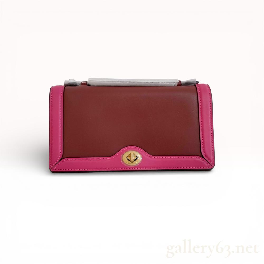 Description
Coach Riley Chain Clutch in colorblock glovetanned leather, contemporary. The exterior features a two-tone burgundy and bright pink palette with an accordion-style construction and brass-toned turn-lock hardware. The interior is lined with a patterned textile and contains three main compartments, a zippered pocket, and an embossed leather creed patch. Includes a retail tag bearing numbers 06118 and 5-0005.
Width: Approximately 8 inches.