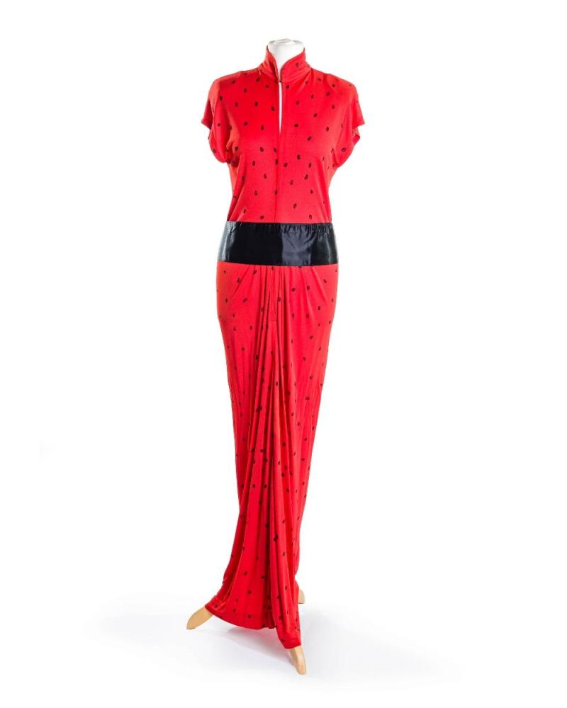 Description
Yuki Torimaru.

Ladybird maxi dress, of coral red with black ladybird caricatures printed throughout the dress, detailed with a mandarin collar with hook-and-eye closure and a frontal zip to the waist, 100% viscose, approx. UK size 10; the lot is also accompanied with a black satin cummerbund 

Grade B 

Provenance: The Casandra Collection

Notes:

Born in Miyazaki, Japan, Yuki Torimaru (also known as Gnyuki) studied architecture before training as a textile engineer, a dual foundation that profoundly shaped his approach to fashion. He moved to London in 1964 and attended the London College of Fashion, graduating in 1966, before gaining valuable experience working for several major fashion houses, including Pierre Cardin. In 1972, he launched his own designer label with a collection for Harvey Nichols, establishing a reputation for technically sophisticated garments distinguished by dramatic cuts and architectural construction. His designs frequently employed panels cut on a full circle, creating garments of exceptional volume, fluidity and luxurious drape, reflecting a refined synthesis of engineering precision and sculptural elegance.