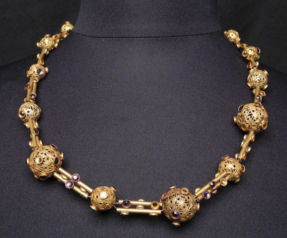 HENRY - circa 1960

Collier en métal doré composé de boules finement ciselées et rehaussés de strass parme et jaune Fermoir crochet Signé