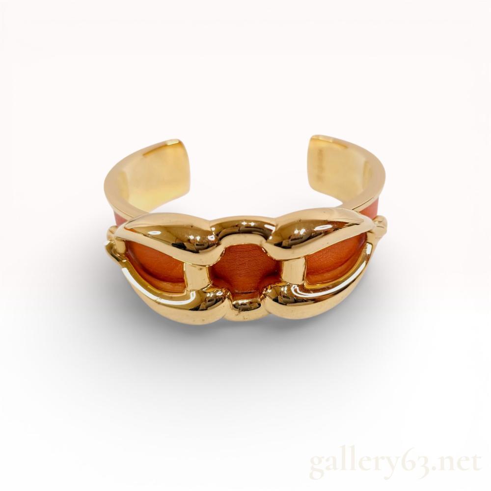 Description
Hermes open cuff bracelet featuring a yellow gold-tone metal frame with a textured orange leather inlay. The design showcases a raised interlocking triple-link motif on the front. The interior is stamped HERMES followed by a square hallmark and is accompanied by a signature orange circular box with bolduc ribbon.
Interior circumference approximately 15.5 cm.