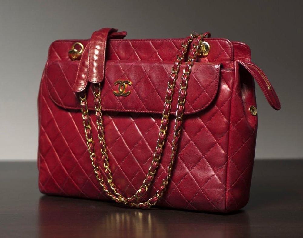 CHANEL

Sac en cuir agneau bordeaux matelassé, deux poches extérieures dont une à rabat siglé, fermeture éclair, double anse chaîne en métal doré entrelacé de cuir (patine). Long: 29 cm