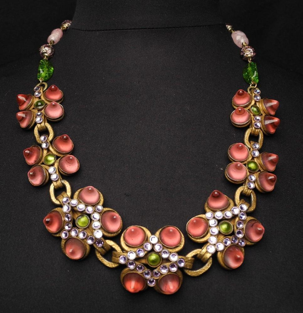 HENRY - circa 1960

Collier articulé en métal doré rehaussé de pâte de verre rose et verte ainsi que de strass monté sur une chaîne entrecoupée de pierres vertes et roses Fermoir crochet Signé au revers d’un des éléments