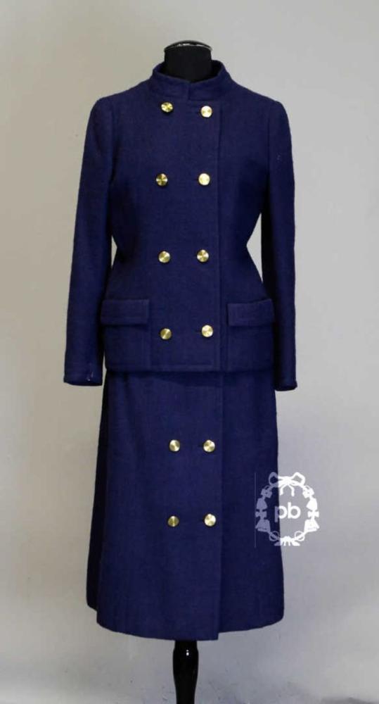 GIVENCHY Haute Couture n°46294, circa 1968/72...

GIVENCHY Haute Couture n°46294, circa 1968/72
 Tailleur en toile de laine marine, veste à col officier légèrement décollé sur double boutonnage en métal doré, manches longues montées, deux poches plaquées à revers, jupe à effet portefeuille, doublure en s
