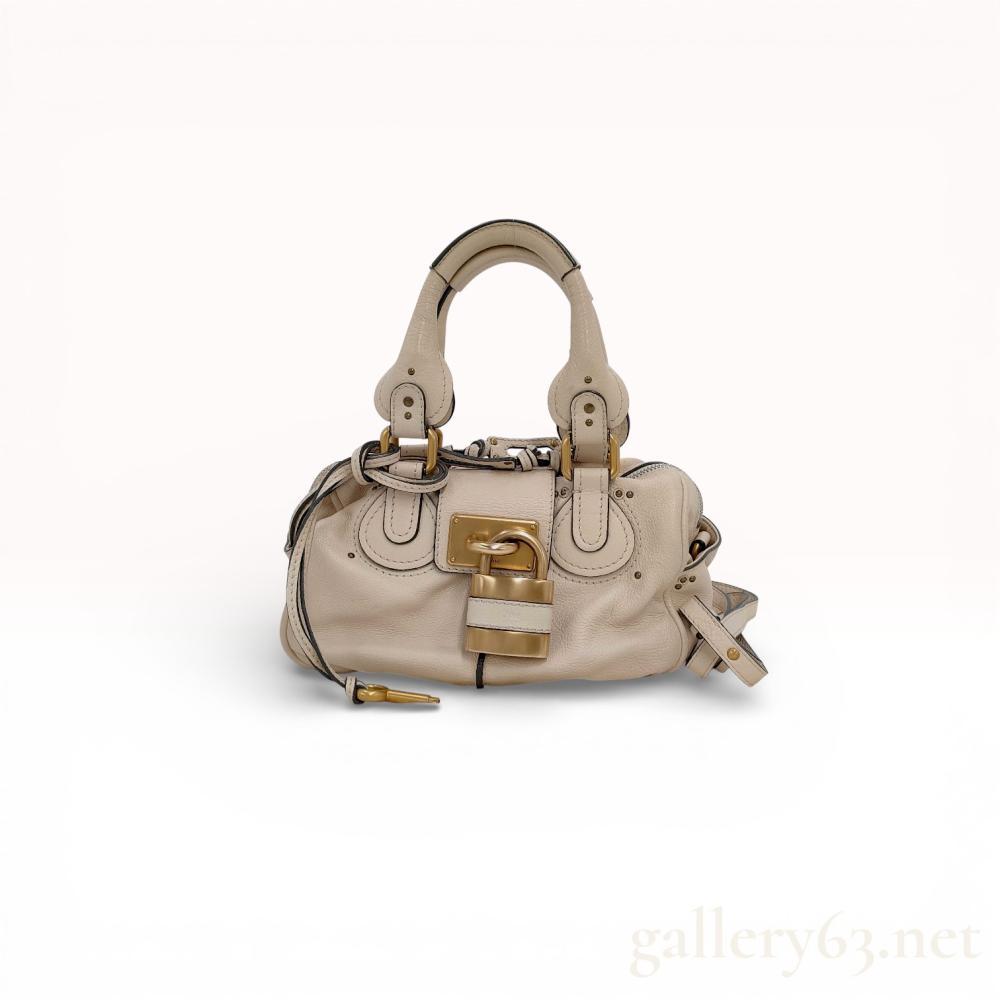 Description
Chloe Paddington satchel crafted from cream pebbled leather with brushed gold-tone brass hardware. The design features a signature oversized functional padlock, a leather-bound key, and double rolled top handles with studded bases. The interior is lined in beige canvas and contains one zippered pocket and one leather slip pocket.
Width: 11.5 inches
Height: 7 inches
Depth: 6 inches.