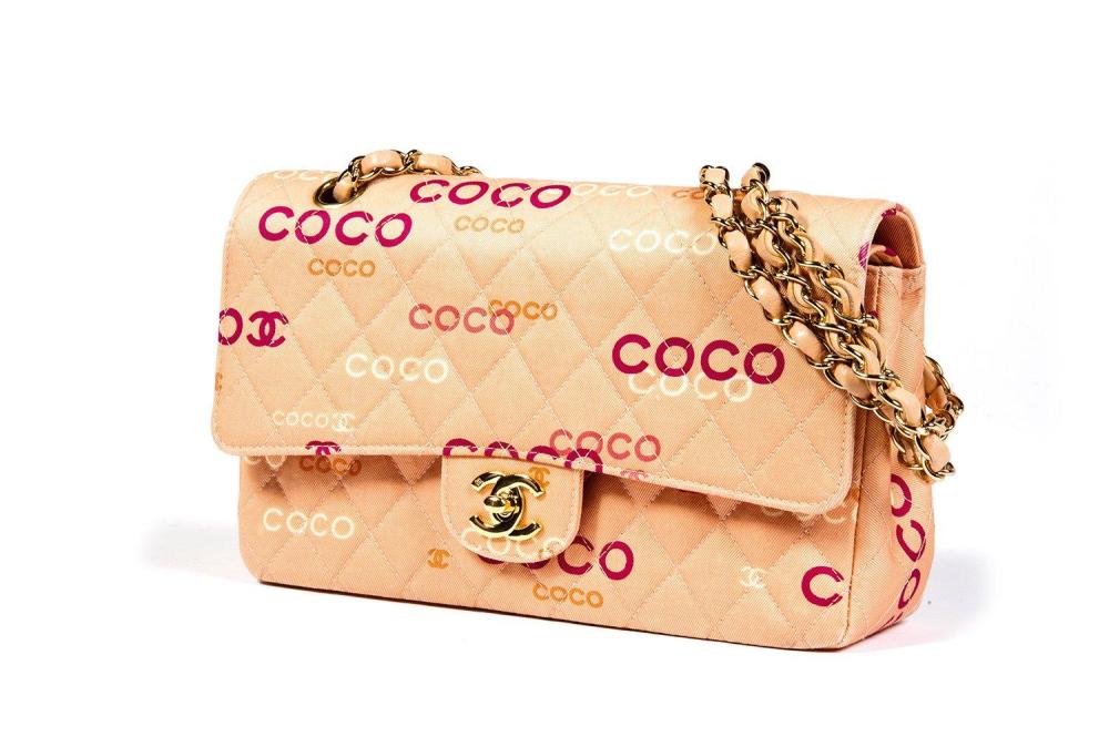 COCO CHANEL

Sac "Timeless" 25cm en coton matelassé rose imprimé du sigle et de "Coco" multicolore, fermoir en métal doré siglé sur rabat, anse chaîne réglable entrelacée de cuir en coordonné, poche extérieure. Bon état (salissures)