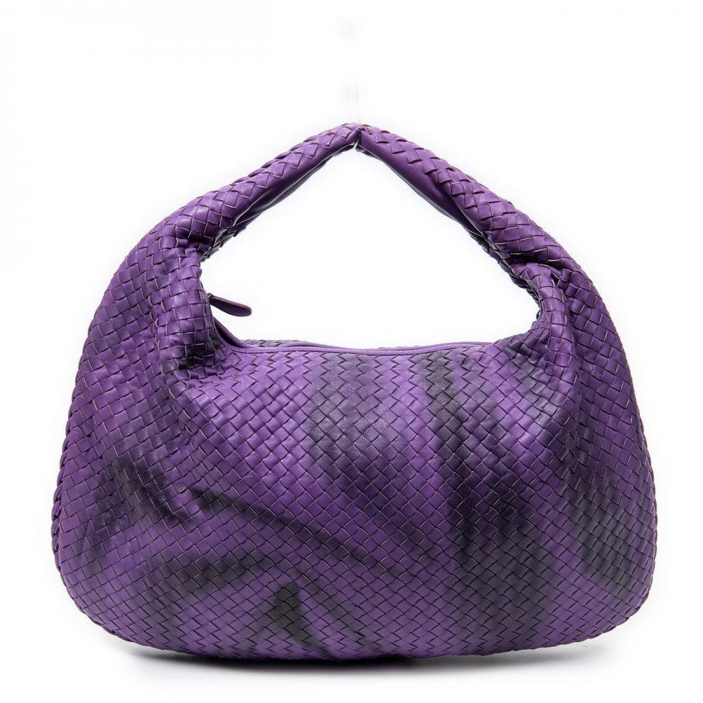 Description


BOTTEGA VENETA
Large Veneta Hobo bag.
In purple Intrecciato calfskin. Short handle and zipper closure. Antiqued brass hardware. Interior with pocket.
With interior numbering.
In perfect condition, barely unused.
Measurements: 52 x 35 x 5 cm.
The Italian brand Bottega Veneta was founded by Michele Taddei in 1966, when the company started producing handcrafted leather goods. The firm created the design made with interlocking leather, ’Intrecciato’, offered on most of its luxury handbags. The simple name ’Bottega Veneta’ translates as "Venice store", which perfectly reflects its understated style. Bottega’s bags do not feature extravagant designs or flashy logos, but rather are elegant and simple. Their bags were famously monogrammed in the 1970s, leading to their famous slogan: "When your own initials are enough.