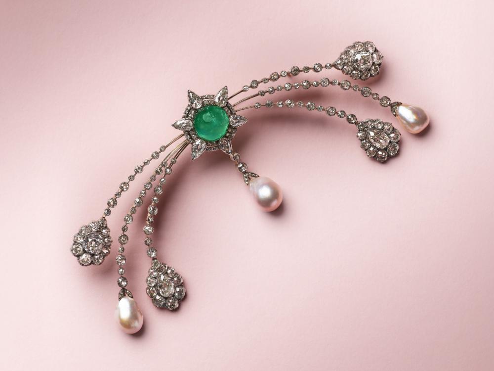 BROCHE ÉMERAUDES, PERLES FINES ET DIAMANTS BELLE ÉPOQUE

Cabochon emerald, drop-shaped natural pearls, pear-shaped, old and rose-cut diamonds, French import marks for 18K yellow gold (750‰) and silver (800‰), circa 1900, Morel & Cie J.Chaumet Successeurs monogrammed fitted case 
LFG, 2026, report n°426182: saltwater natural pearls, measuring approximately 9.1 x 12.5 mm, 10.2 x 12.7 mm and 9.5 x 12.2 mm, no indication of treatment. One natural emerald, Colombia, minor oil 
Gam Paris, 2026, report n°20261978826-2: Colombia, moderate oil 
Emerald: for an approximate weight of 10.00 - 13.50 carats 
Natural pearls: measuring approximately 13.50 x 10.20 x 10.06 mm, 12.97 x 9.05 x 7.25 mm and 11.90 x 9.45 x 6.38 mm 
Diamonds: for an approximate total weight of 12.50 - 15.50 carats 
Size/Dimensions: 12.3 x 5.0 cm 
Gross weight: 38.73 grams 
Please note that this brooch is not signed by Chaumet. Research carried out in conjunction with the Heritage Department of Maison Chaumet has not identified any record of this commission among the numerous family orders held in the Maison’s archives. 
Veuillez noter que cette broche n’est pas signée Chaumet. Les recherches effectuées en collaboration avec le département Patrimoine de la Maison Chaumet n’ont pas permis de retrouver cette commande parmi les nombreuses commandes de la famille répertoriées dans les archives de la Maison. 
 Please note that this lot was tested by Pourquery DMP as gold (750‰) and silver (800‰), but was exempted from assay marking due to fragility. 
Veuillez noter que ce lot a été testé par Pourquery DMP comme étant composé d’or (750‰) et d’argent (800‰), mais qu’il a été dispensé de poinçonnage pour fragilité.