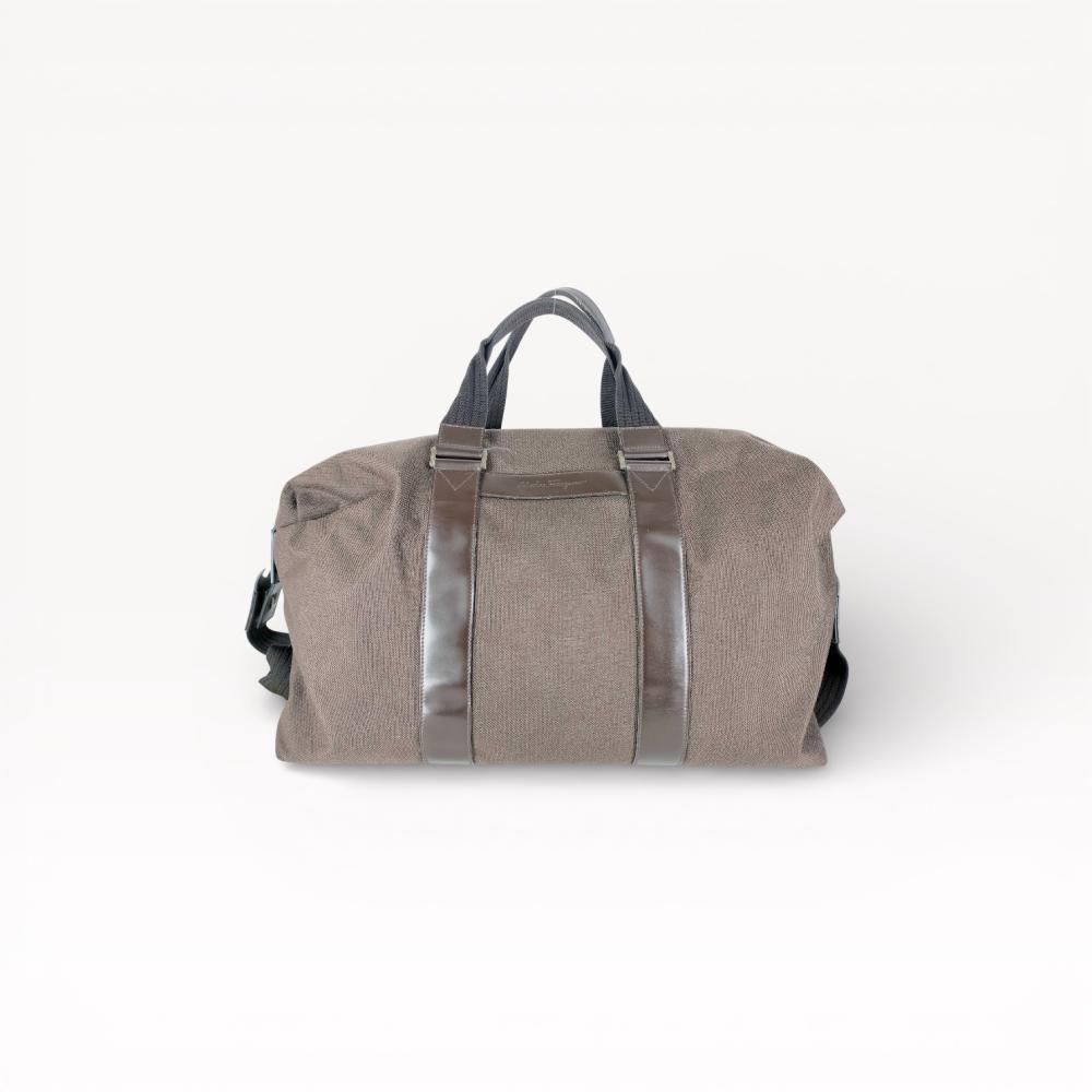 Description
Salvatore Ferragamo large weekender duffle bag featuring a dark brown textured canvas body with smooth brown leather trim and vertical bands. The design includes dual top handles of black woven webbing and leather, polished silver-toned hardware engraved with the brand name, and a debossed signature on the exterior leather patch. The interior is lined with brown canvas and contains a leather brand label.
Approximately 20-22 inches length.