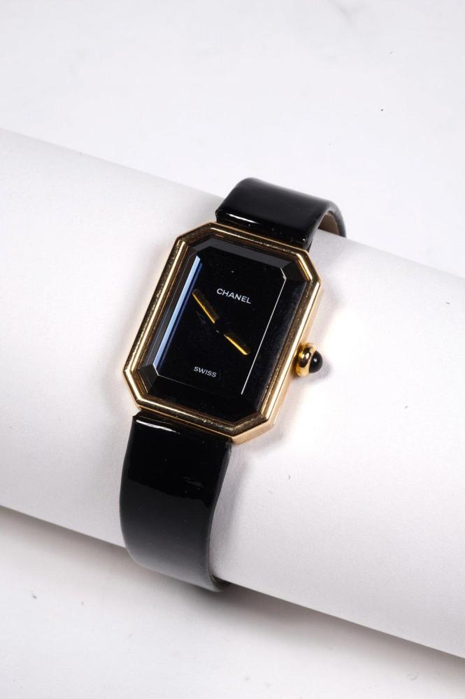 CHANEL

SWISS MADE N°U.S.49204 Montre "Première" en or jaune, cadran noir, verre biseauté, mouvement quartz, bracelet en cuir vernis noir, fermoir plaqué or. Pds total: 29,9 grs environ. Longueur: 15cm