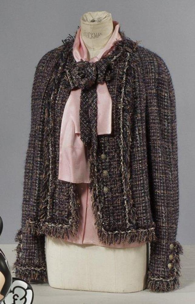 CHANEL

Veste en tweed chiné multicolore à dominante violine rehaussé de lurex gansé d’une natte à effet effiloché, encolure ronde, simple boutonnage, manches longues; fleurs de même tissu agrémentant la veste