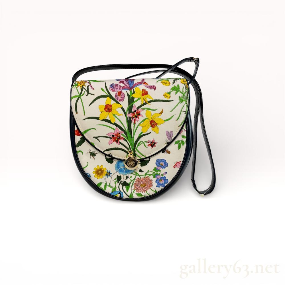 Description
Authentic Gucci shoulder bag featuring the house floral print on a light ground. Rounded saddle-style silhouette trimmed in black leather with a coordinating shoulder strap. Flap front secured with a gold-tone circular Gucci emblem closure. Interior lined in dark leather with interior pocket and Gucci label present. Design associated with vintage Gucci floral collections.