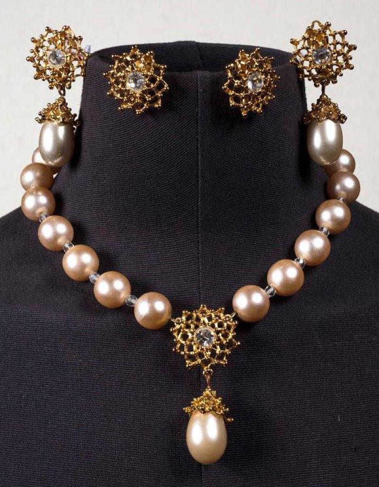 YVES SAINT LAURENT

Collier de perles blanches entrecoupées de perles translucides orné au centre d’un motif en métal doré serti d’un strass façon brillant rehaussé d’une goutte, fermoir à l’identique souligné de coeurs gravés du nom du couturier, nous y joignons une paire de pendants et une paire de boucles d’oreille. Signé
