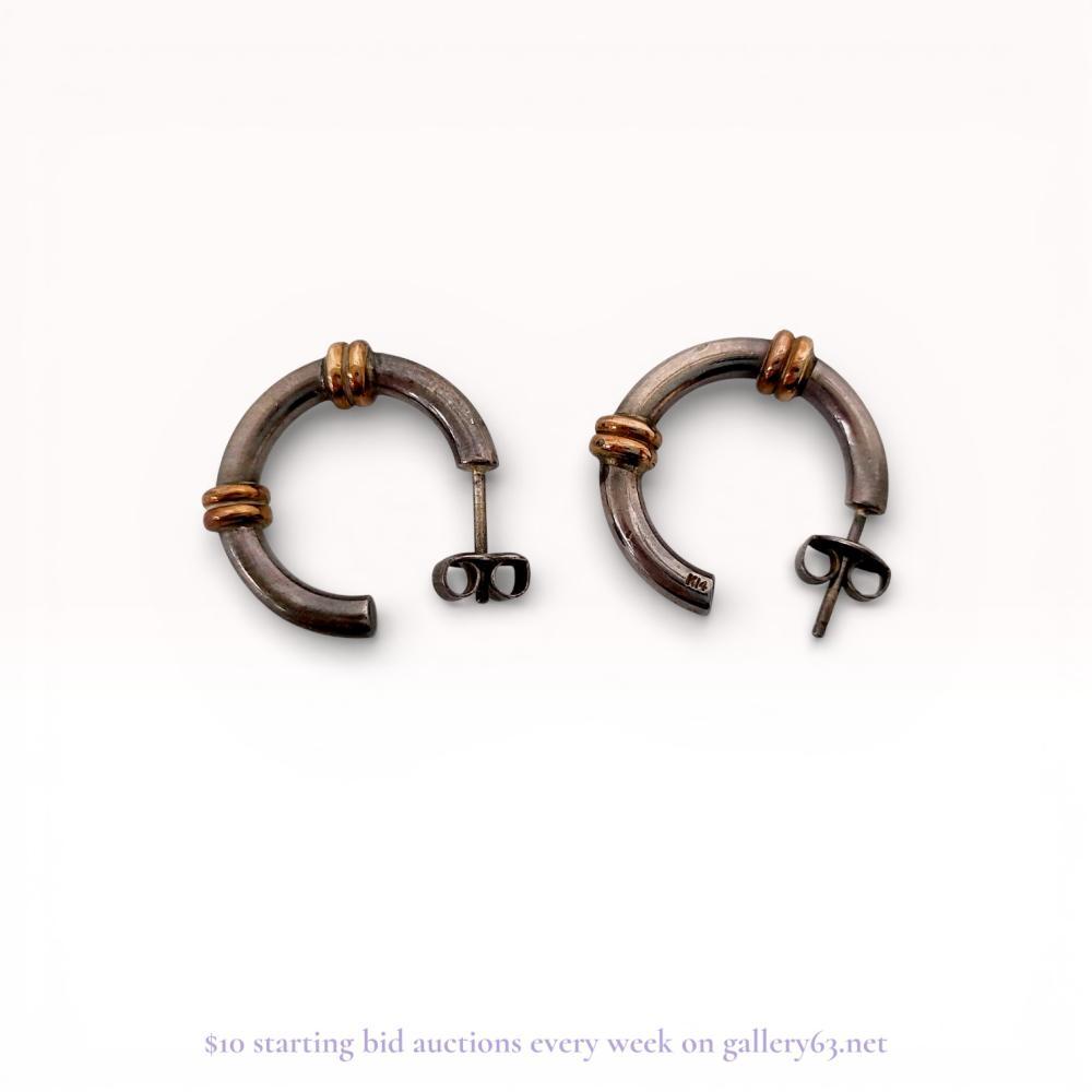 Description
A matched pair of C-hoop style earrings featuring a polished sterling silver body with two double-ribbed 14 karat gold accent bands. The design is characteristic of mid-to-late 20th-century American jewelry. Each earring is secured with a post and butterfly friction backing. The interior ends are incised K14 and the backings are stamped Ster 925.
Diameter: Approximately 20mm.