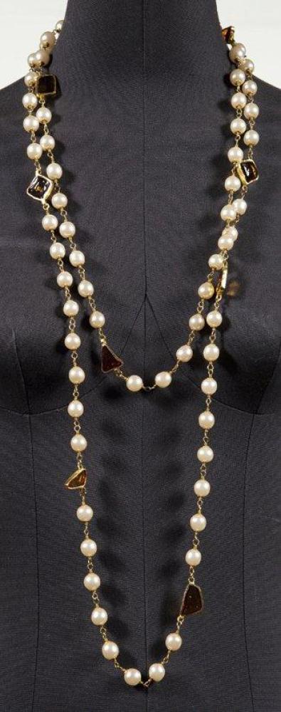 CHANEL CIRCA 1994

Long sautoir composé de perles blanches entrecoupées de cabochons de résine façon citrine, serti de métal doré. Signé. Long.: 95 cm