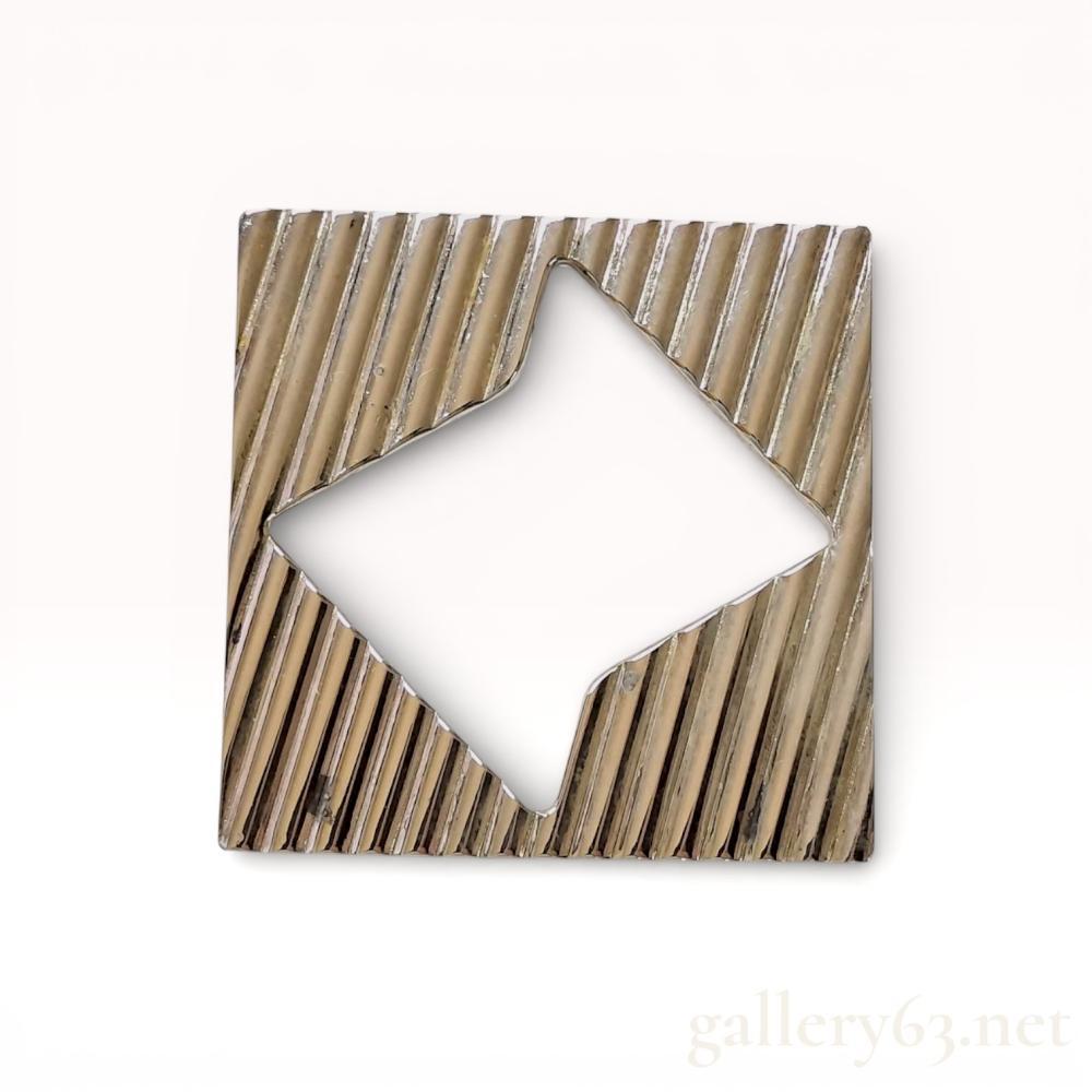 Description
Tiffany and Co. sterling silver modernist brooch featuring a square silhouette with a central diamond-shaped aperture. The front face is decorated with a diagonal reeded texture, while the reverse is finished in high polish and equipped with a revolving safety clasp and integrated pendant hook. The back is stamped TIFFANY and CO STERLING SILVER alongside a small diamond-shaped hallmark containing the letter L.
40mm x 40mm.