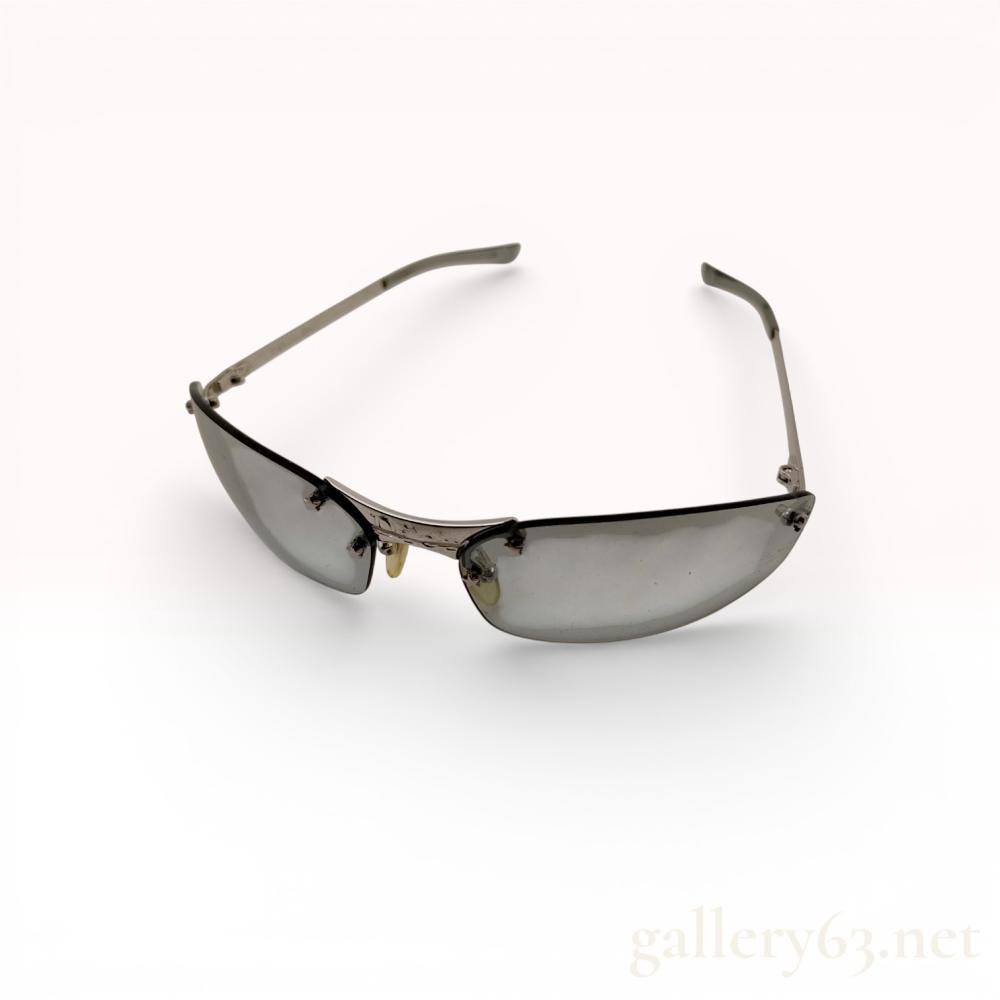 Description
Christian Dior MiniPop rimless shield-style sunglasses, early 21st century. Features light blue-tinted wrap-around lenses, silver-toned metal hardware, and grey translucent temple tips with star accents. Marked Dior on the bridge and internally inscribed Christian Dior, Made in Austria, and model code YB7I4. Accompanied by a branded hard case, microfiber drawstring pouch, and product literature.
65-15 120.