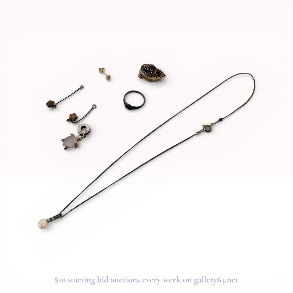 Description
An assortment of jewelry featuring a Pandora sterling silver turtle dangle charm and two Scandinavian sterling silver flower charms. The lot includes a teardrop-shaped marcasite and red stone clip-on earring, a pearl pendant necklace, an abalone shell inset ring, and a gold-toned stud. Pieces bear marks including S 925 ALE, 925S with a triangle over diamond maker’s mark, and 925.
Necklace length: approximately 40 cm
Turtle charm length: approximately 2 cm.