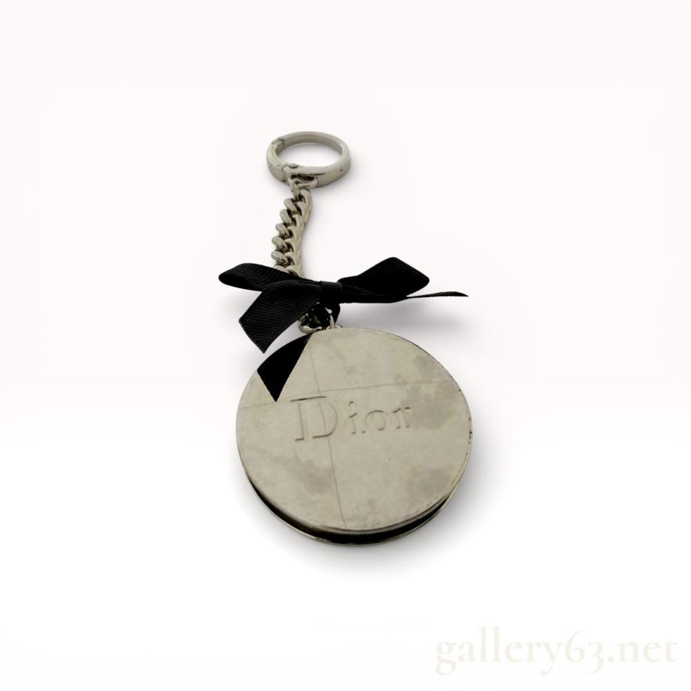 Description
Dior Beaute folding purse hanger and keychain featuring a circular silver-tone metal body with an articulated hook arm and magnetic closure. The accessory is accented with a black grosgrain ribbon bow and attached to a spring-loaded circular key ring via a curb-link chain. The front face is embossed with the Dior logo, and the reverse is fitted with a black non-slip pad marked Dior beaute.
Main Body Diameter: Approximately 1.75 inches (4.5 cm)
Total Length: Approximately 4.3 inches (11 cm).