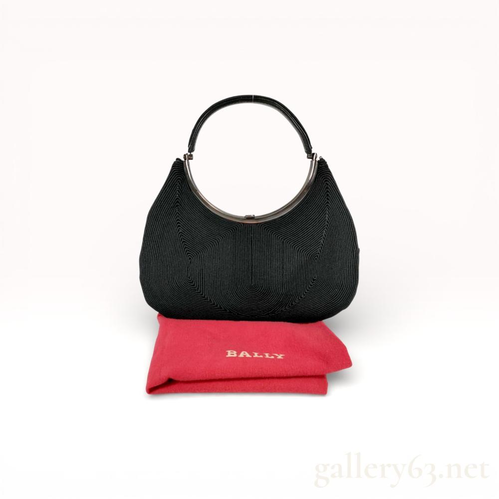 Description
Bally vintage evening bag, mid to late 20th century. This piece features a black corded passementerie exterior in a concentric pattern, a gunmetal-tone crescent metal frame, and a matching corded top handle. The interior is lined with black ribbed fabric, containing one slip pocket and an applied black plaque with the BALLY mark. Includes a red branded dust bag.
Width: 9.5 inches
Height: 6 inches (excluding handle).