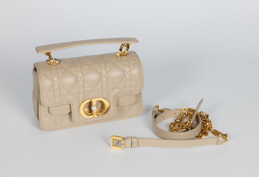 Description

DIOR
Jolie Top Handle bag.
In ivory calfskin with cannage stitching and gold hardware. Features a double flap enhanced by the gold-tone metal clasp appliqué. Detachable short top handle and removable gold-colored link handle with leather trim. Three compartments and one zippered pocket.
Measurements: 19 x 12 x 7 cm.

The Jolie Top Handle bag by Dior is part of the recent evolution of the maison, which has sought to recover and reinterpret the historical codes of the house with a contemporary sensibility. Its design is part of the tradition of structured top-handle bags, a typology closely linked to feminine elegance promoted by Dior since the time of Christian Dior and the New Look of the late 1940s.