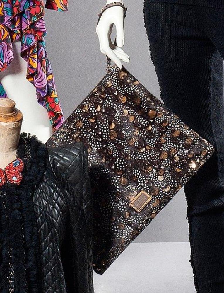 VALENTINO Garavani

Pochette en vachette façon poulain imprimée à motifs de plumes de perdrix, fermetures Eclair, dragonne, face ornée d’une plaque de laiton doré et cuir.