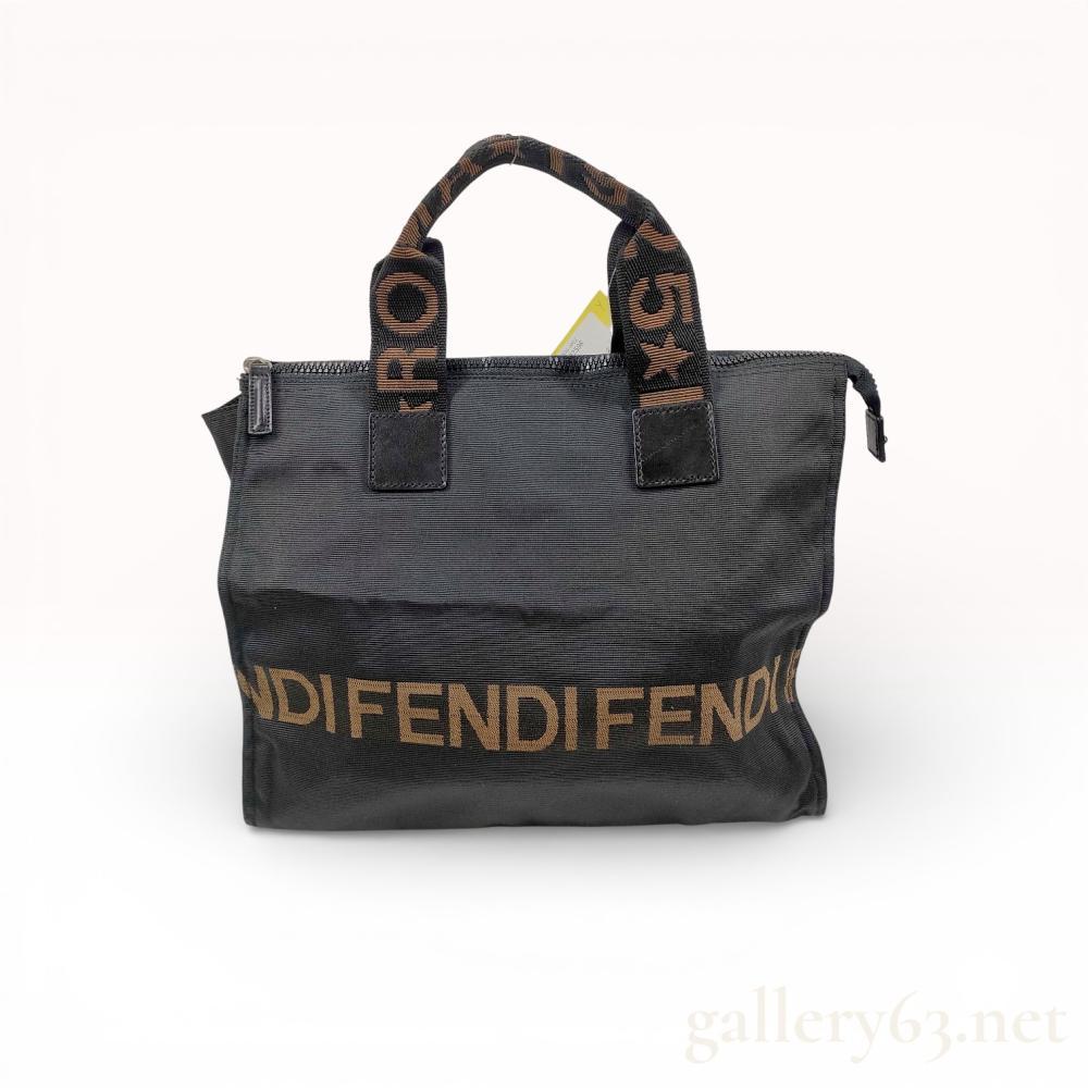 Description
Fendi small rectangular tote bag in black ribbed canvas. The exterior features a woven tan logo band at the base and twin woven webbing handles marked Fendi Roma with a star symbol. Construction includes leather handle patches, a top zipper closure with leather pull, and a horizontal exterior zippered pocket on the reverse; no serial or date codes are visible.
11 inches W x 8.5 inches H x 4 inches D.