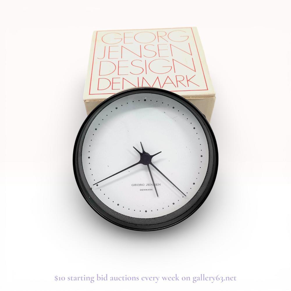 Description
Georg Jensen wall clock designed by Henning Koppel, late 20th century. The timepiece features a circular matte black case housing a minimalist white dial with black dot indices and three central hands. The dial is marked Georg Jensen Denmark, and the reverse retains a manufacturer label and integrated hanging bracket. This lot includes the original red-lettered retail presentation box.
Approximately 4 inches (10 cm) in diameter.