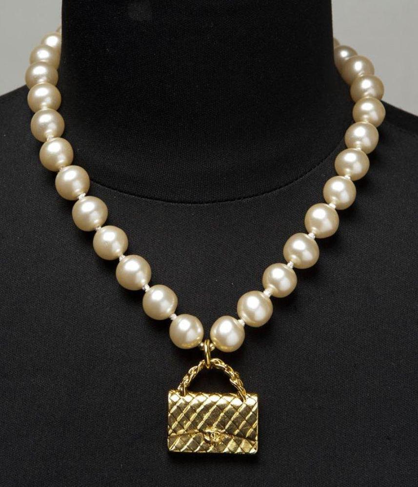 CHANEL, circa 1994

Collier de perles blanches rehaussées au centre du sac 2.55 en métal doré. Signé