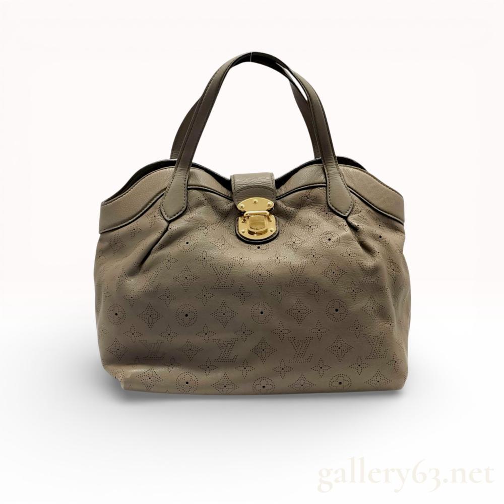 Description
Louis Vuitton Mahina Cirrus PM handbag in taupe perforated leather. This drummed calfskin bag features the perforated Monogram pattern, dual flat handles, and a gold-tone push-lock closure. The interior is lined in dark grey Alcantara with a zippered pocket and D-ring, while the exterior base is protected by four branded feet. The leather tab is stamped LOUIS VUITTON PARIS and hardware is marked with the house name.
Base Width: 14.5 inches
Height: 10.5 inches.