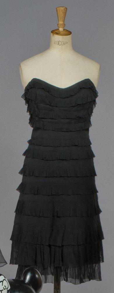 CHANEL

Haute couture, circa 1960 Robe de cocktail en mousseline noire, haut bustier, effet de volants plissés soleil sur jupe évasée (manque bretelles). Griffe noire, graphisme blanc