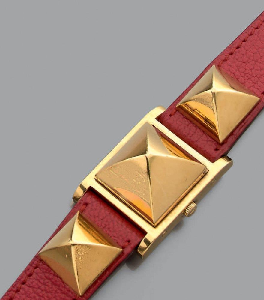 HERMES

Medor Contemporaine Modèle de dame plaqué or à quartz. Cadran blanc 4 index aiguilles or. Boitier avec un capot en forme de clou. Bracelet rouge orné de clous dorés. Ecrin d’origine. Pile à changer Dim 23x23mm