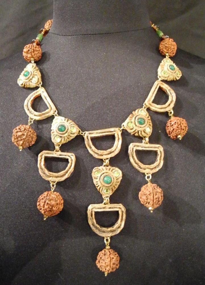 HENRY - circa 1960

Collier composé de pendants en résine gravé rehaussé pour certains de cabochons et strass en pâte de verre verts monté sur une chaîne en métal doré entrecoupés de pierres vertes et marron Fermoir crochet Signé au revers d’un des éléments