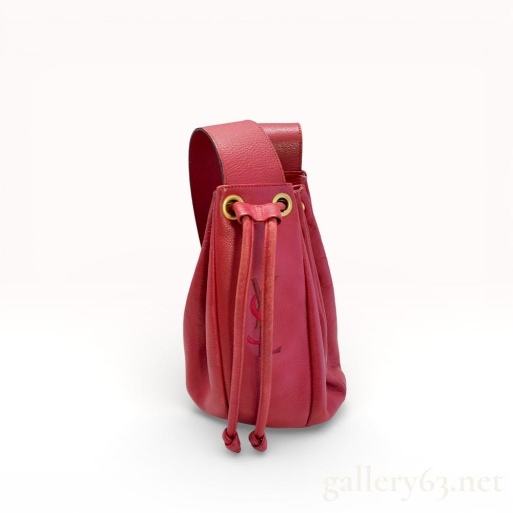 Description
Vintage Yves Saint Laurent drawstring bucket bag in raspberry pink pebbled leather. This piece features a tonal embossed YSL monogram, gold-tone grommets with a leather cord closure, and a structured base with four metal feet. The interior is lined with black textile and includes a single zippered pocket and a gold-tone metal plate marked Yves Saint Laurent Made in France.
Approximately 8 inches (H) x 6 inches (W) at the base.